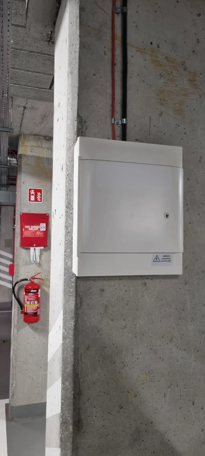 Rozdzielnica elektryczna z naklejką ostrzegawczą na słupie garażu podziemnego, punkt ładowania po uzgodnieniach projektu z OSD, Bemowo Warszawa