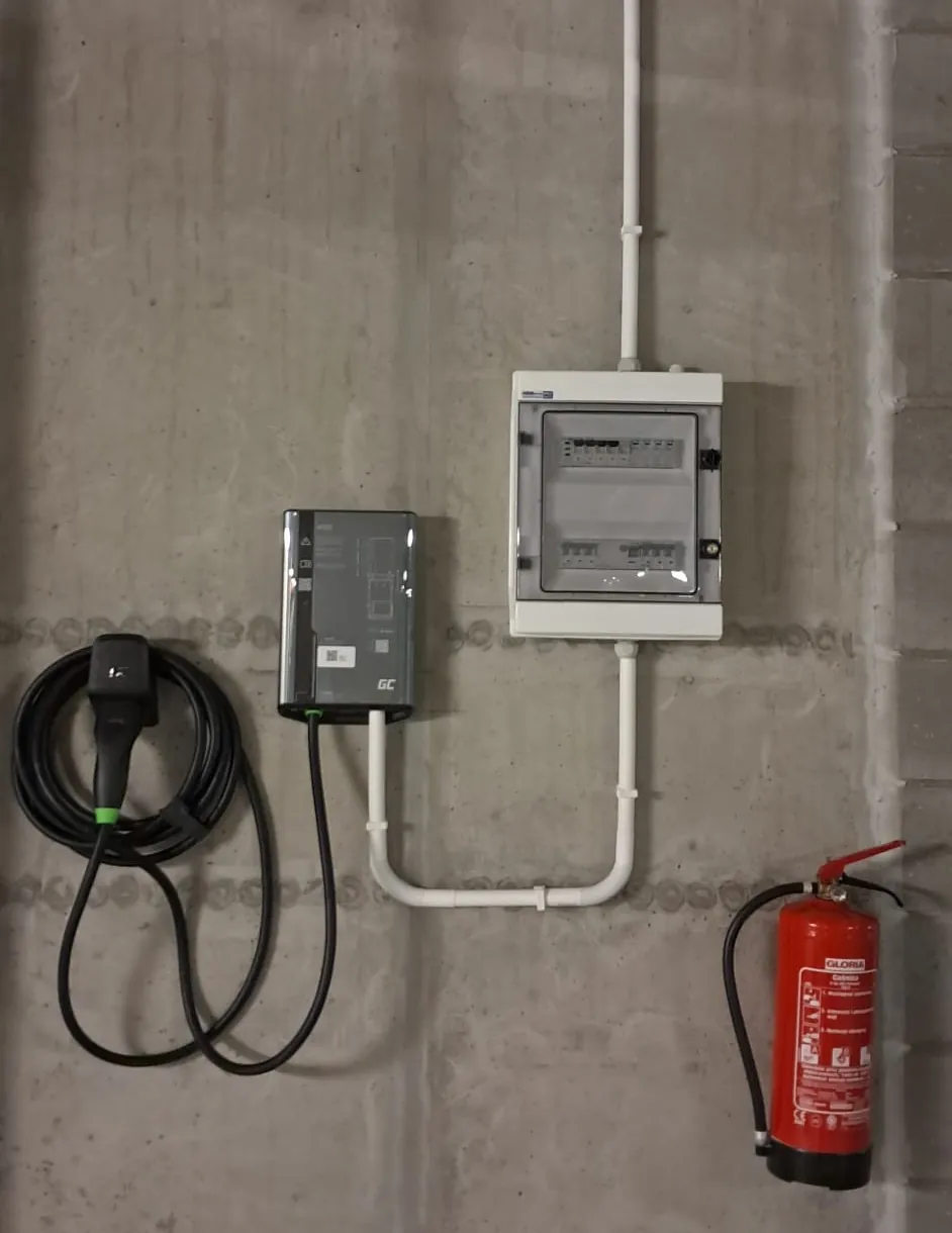 Ładowarka Green Cell HabuDen 11 kW i rozdzielnica z zabezpieczeniami na ścianie garażu podziemnego, trasa kablowa w rurach instalacyjnych, Ursynów Warszawa